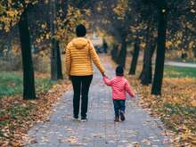 Frau und Kind Hand in Hand in einer Allee